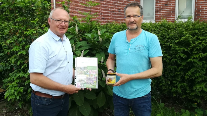 Der erste Vorsitzende des Imkerverein Uelsen überreicht Hajo Bosch ein Glas Uelser Honig